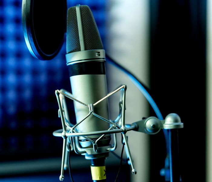 Close up studio condenser microphone with pop filter and anti-vibration mount live recording with color lights background. Side view. Closeup..